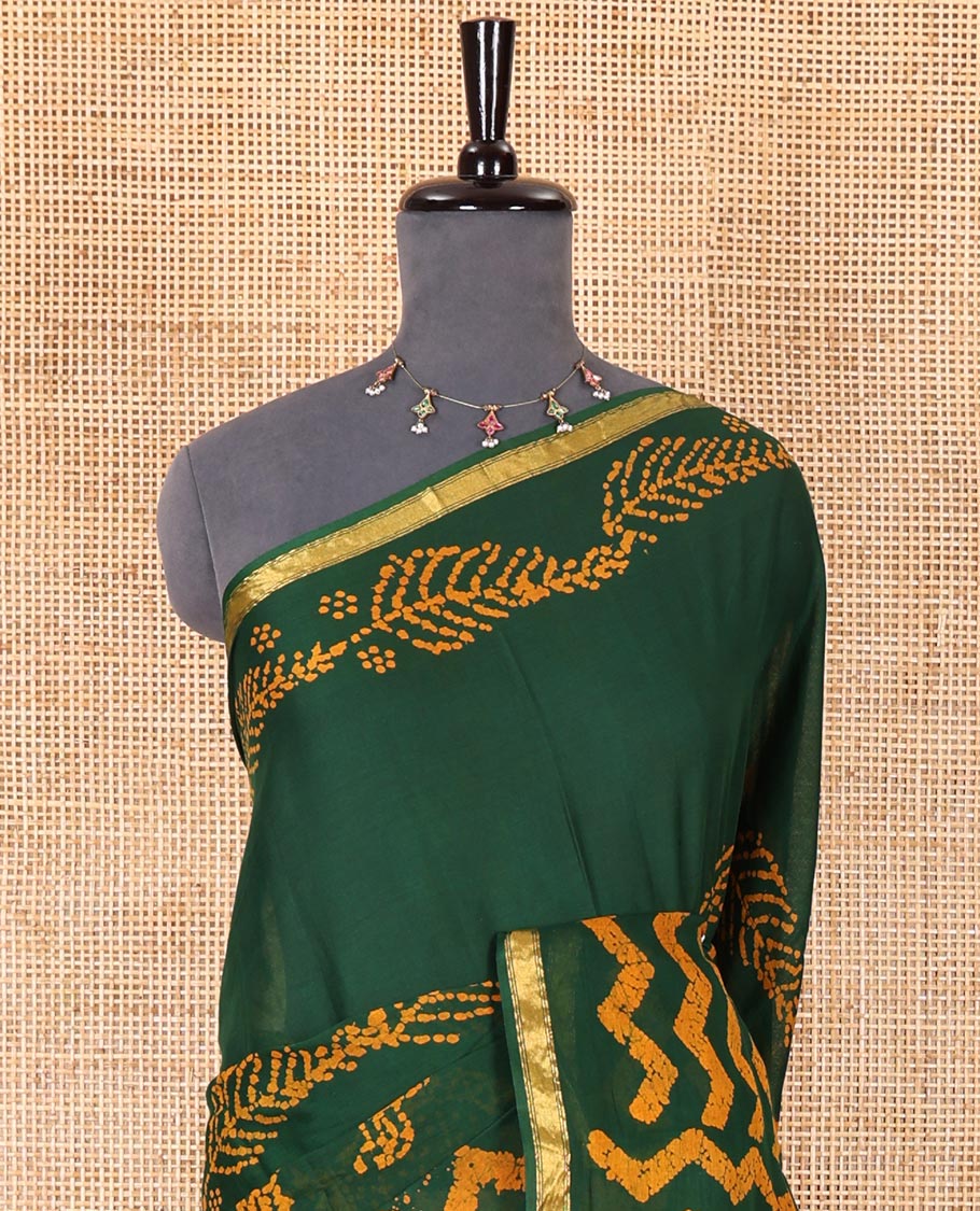 Green wax batik-style zig-zag printed pure cotton saree, gold zari piping border, human figurines batik printed pallu, and a matching blouse