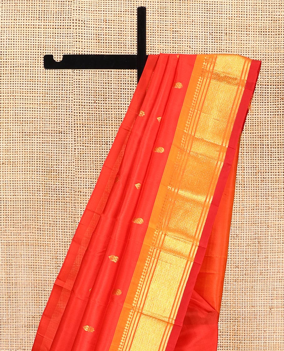 Orange Kanchipuram Silk Saree, Bedecked with Zari Buttas All Over Its Body, Complemented by a Contrast One-Sided Border of Panner Sombu, Banaras, and Mayil Kann Designs, Pallu of Zari Designs, and Comes Without a Blouse