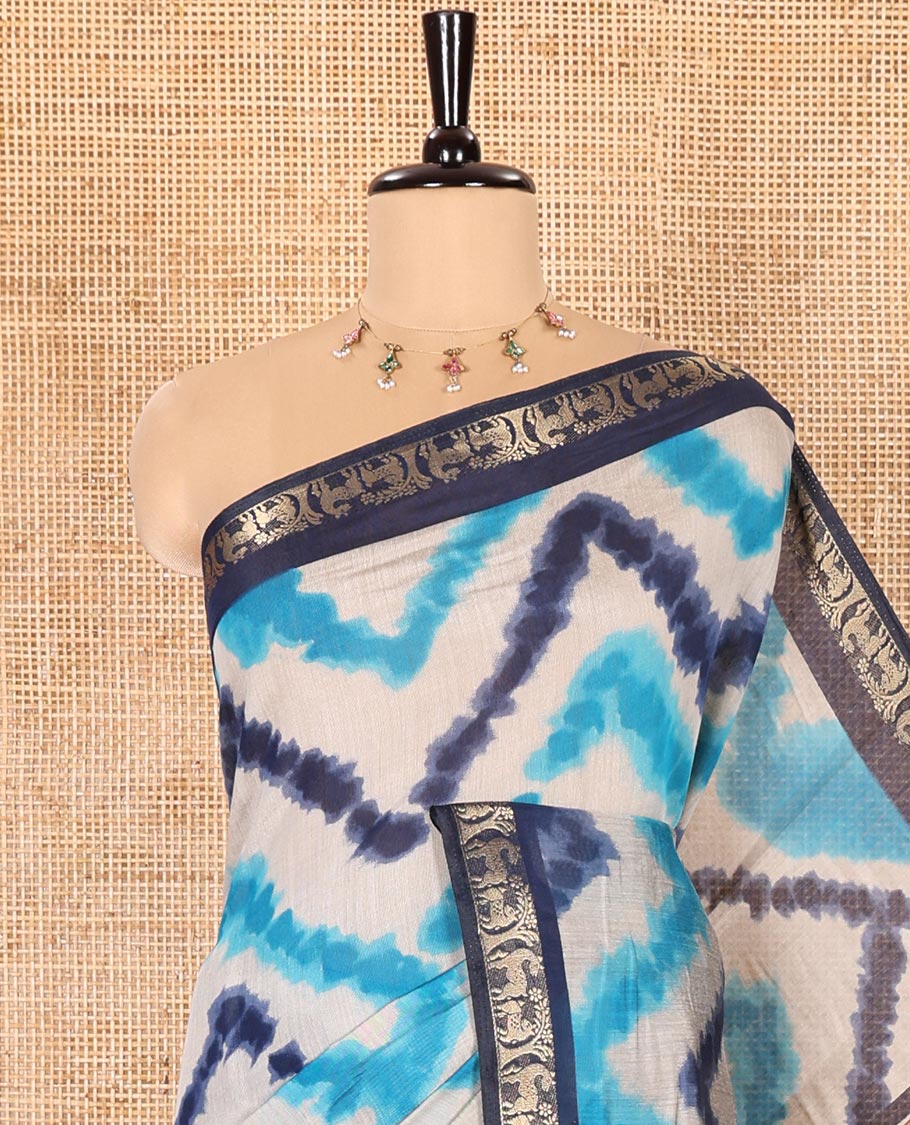 Blue Muslin Cotton Saree Adorned with Zig-Zag Shibori Patterns Prints, Complemented by a Contrast Border of Deer Motifs in Zari, Pallu Decked Up with Scenery Print, and Paired with a Contrast Polka Dots Printed Blouse