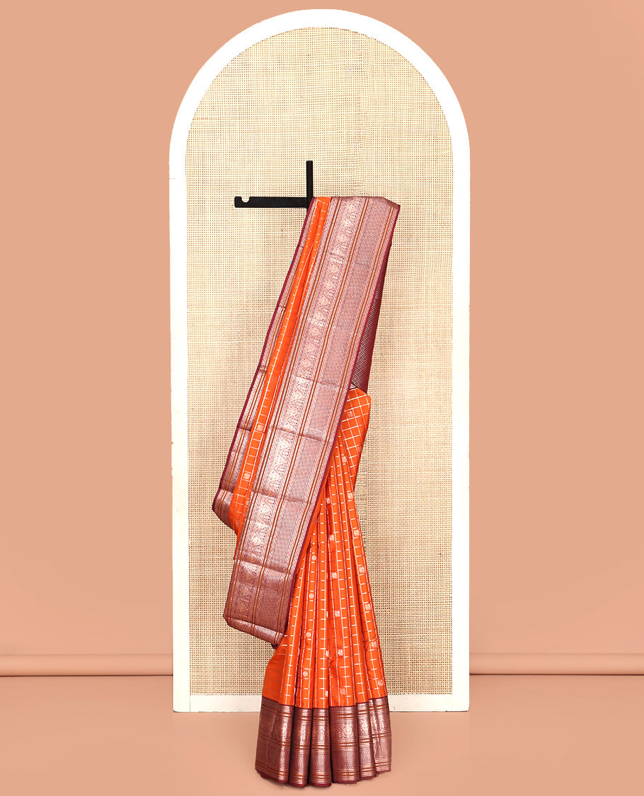 Orange Vasundhara Silk Saree, Meticulously Crafted with Zari Butta Enclosed Checks, Complemented by Contrast Border of Thilakam Mokku, Rettai Neli, Iruthalai Pakshi, and Ara Maadam Designs, Grand Jaal Pallu and Paired with a Contrast Blouse