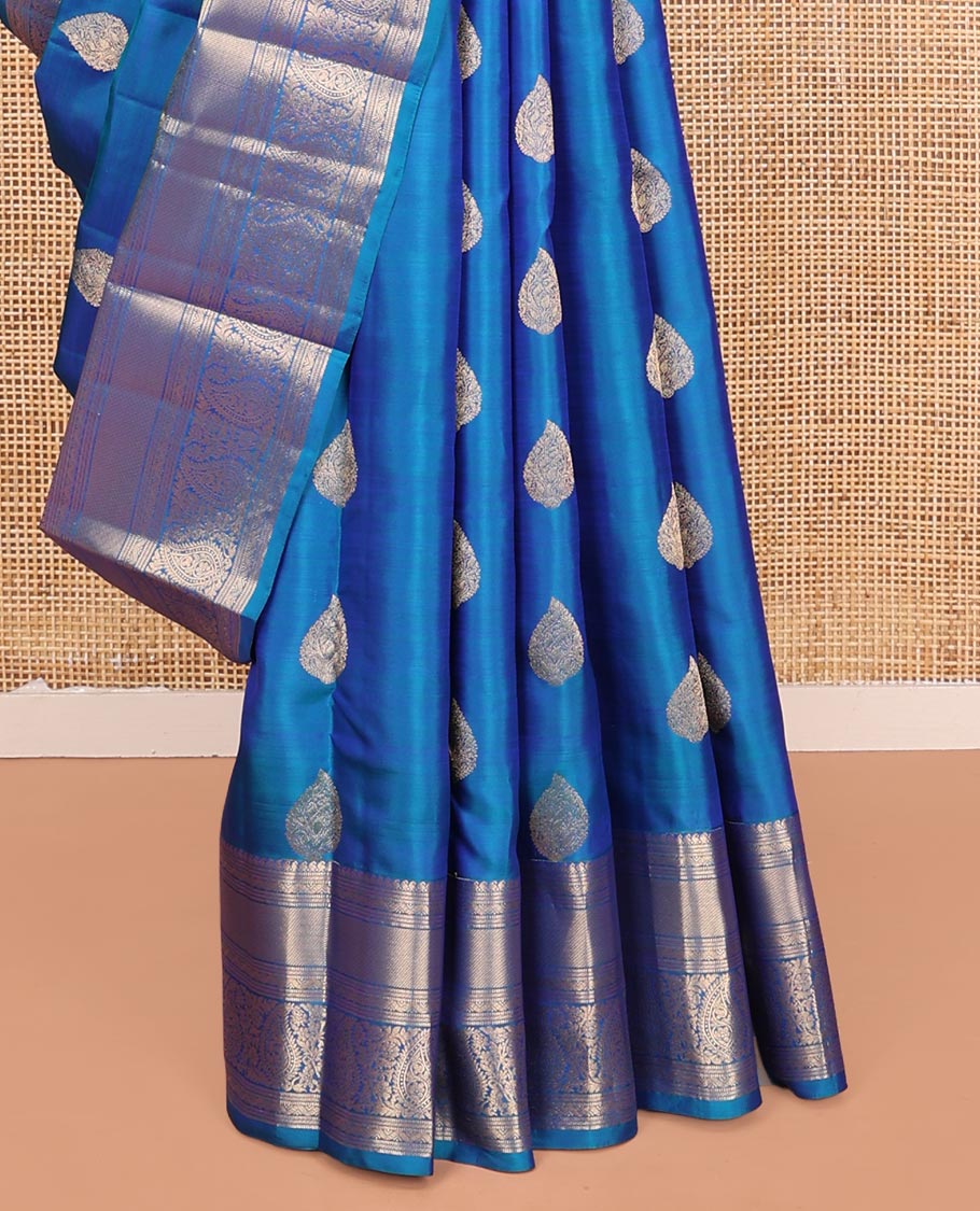 Blue Vasundhara Silk Saree, Mesmerized with Zari Buttas on Its Body, Highlighted by a Zari Border of Manga Mokku, Muthu, and Arumbu Manga Designs, Pallu Steeped with Leaf Designs, and Paired with a Matching Blouse