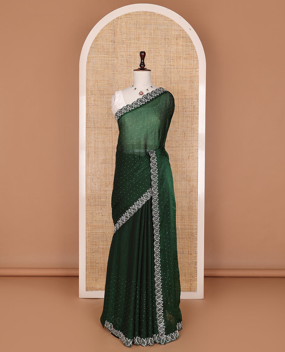 Deep forest green designer saree features gleaming crystal stone embedded all-over its body, scallop leaf motifs embroidered border