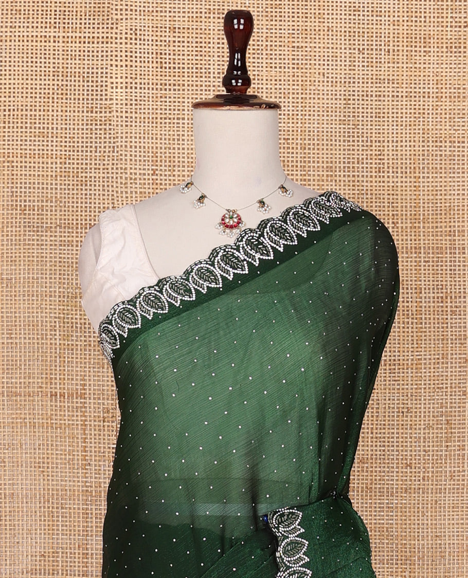 Deep forest green designer saree features gleaming crystal stone embedded all-over its body, scallop leaf motifs embroidered border