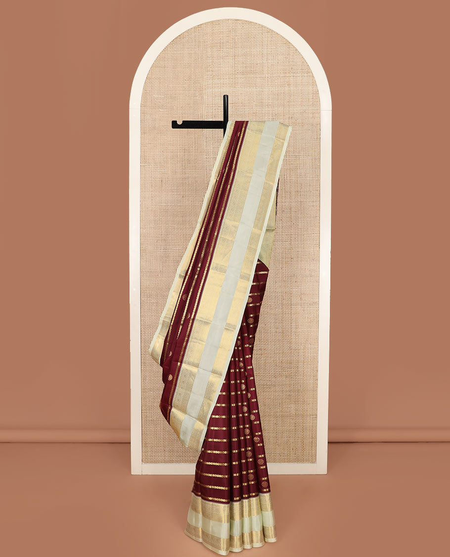 Maroon Vasundhara Silk Saree Richly Detailed with Zari Buttas and Zari Designs, Complemented by a Contrast Rettai Pettu Border of Round Mayil Designs, Subtly Designed Pallu of Floral Jaal Designs, and a Contrast Blouse