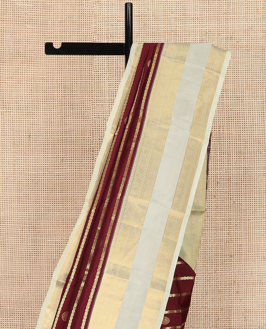 Maroon Vasundhara Silk Saree Richly Detailed with Zari Buttas and Zari Designs, Complemented by a Contrast Rettai Pettu Border of Round Mayil Designs, Subtly Designed Pallu of Floral Jaal Designs, and a Contrast Blouse