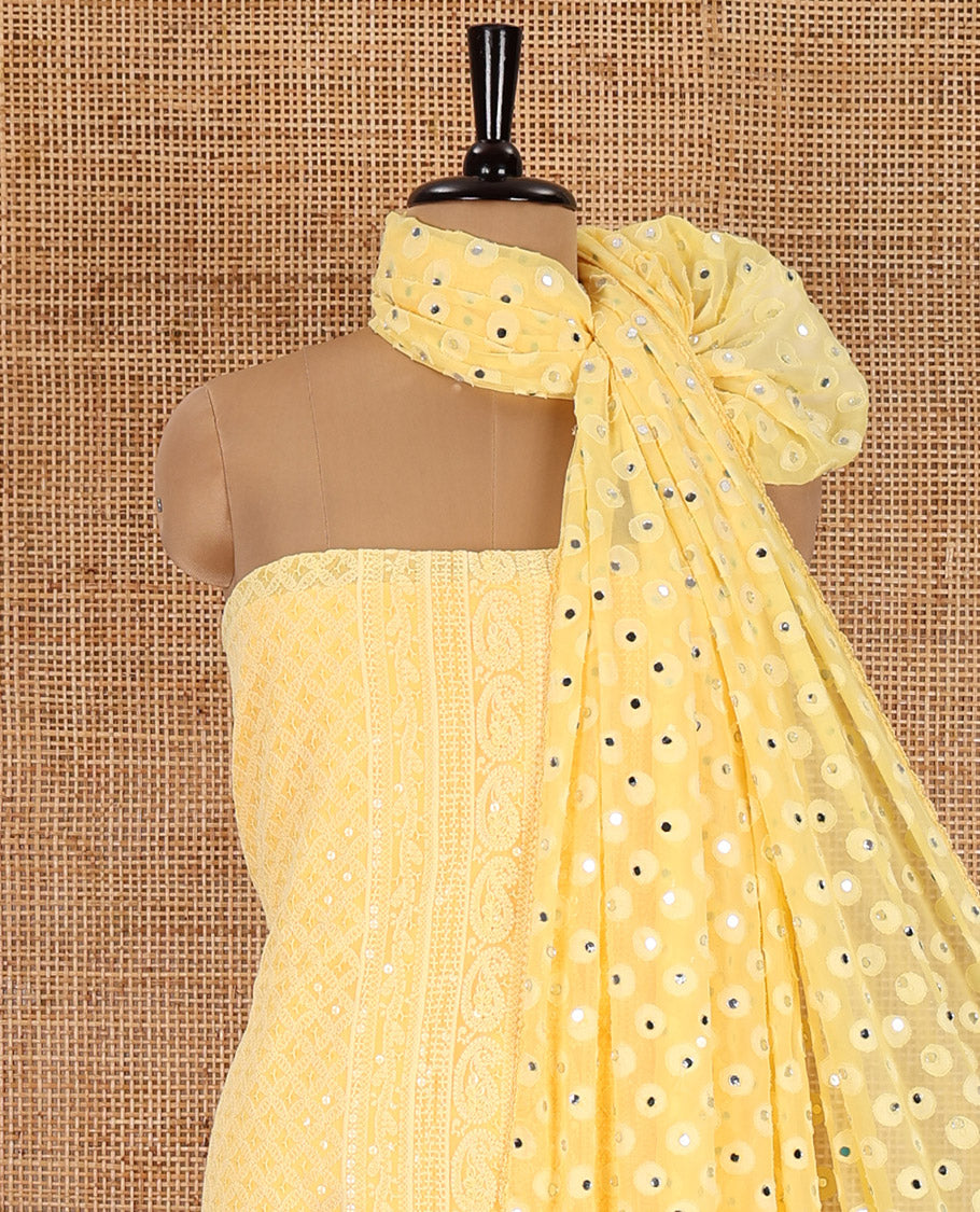 Yellow material chudidar set, paisleys and jaal schiffli sequins embroidered mul georgette top, a matching bottom, and a mirror work dupatta