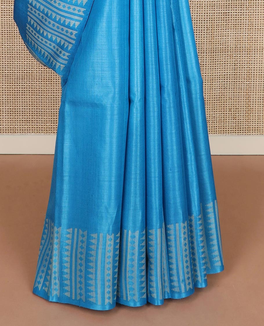 Sky blue plain tussar silk saree, self border and pallu features geometric patterns, and temple motifs