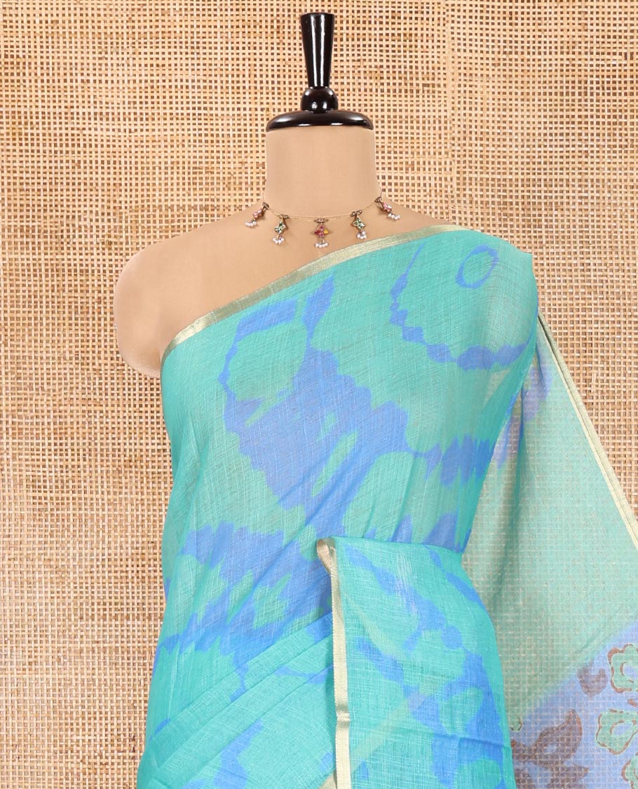 Rama Green Linen Cotton Saree, Elevated with Shibori Printed on Its Body, Subtle Piping Border, Pallu Features Floral Print, and Paired with a Contrast Floral Printed Blouse