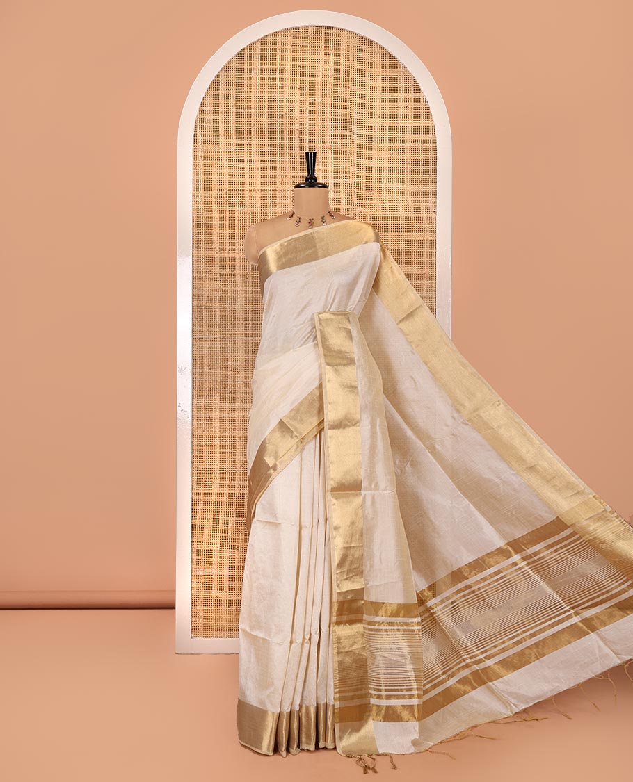 Cream Plain Art Tussar Saree, Highlighted by a Gleaming Golden Zari Bavanji Border, Pallu Steeped with Zari Stripes, and Paired with a Matching Blouse