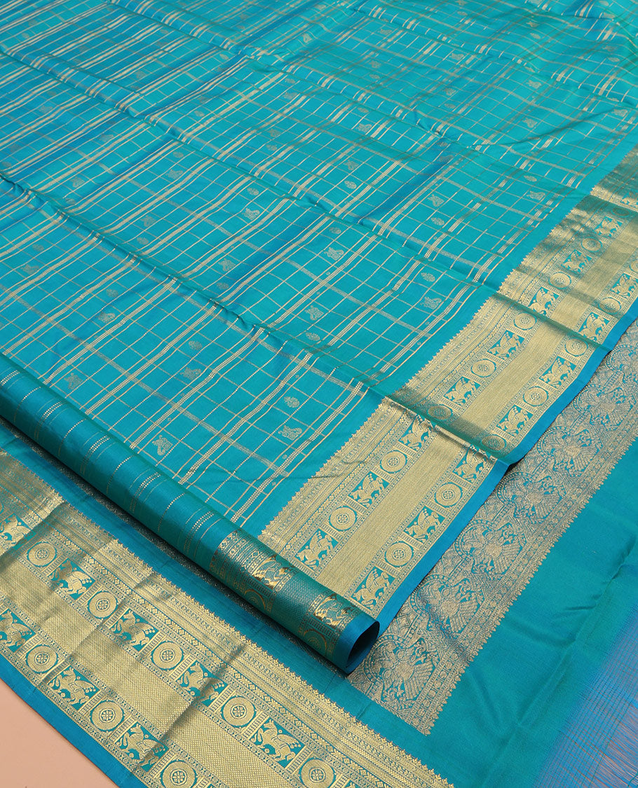 Neelambhari - Peacock Blue Vasundhara Silk Saree Gleamed Up with Zari Buttas Enclosed in Zari Checks, Featuring a Zari Border of Kuthirai and Chakra Designs, Rich Zari Pallu, with a Matching Blouse