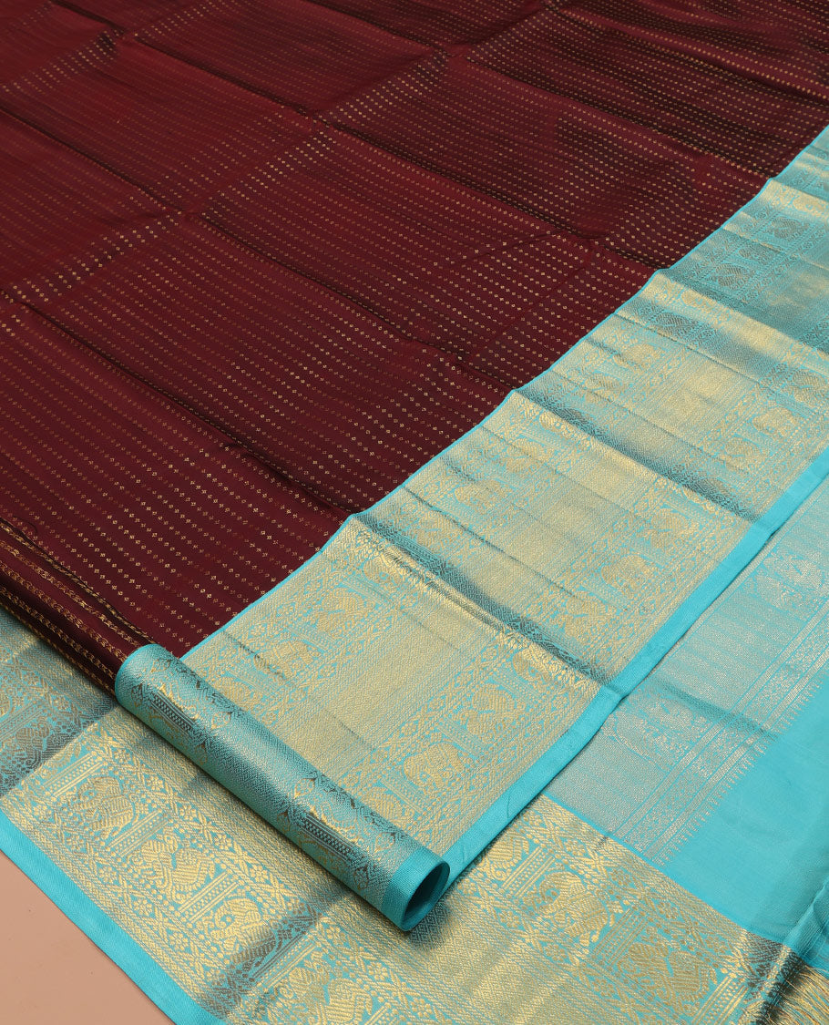 Brown Vasundhara Silk Saree Delicately Woven with Zari Buttas, Highlighted with a Contrast Border of Cross Kamalam, Mayil, Banaras, Yaanai, and Mayil Kann Designs, Pallu Grandly Woven with Jaal Designs, and Paired with a Contrast Blouse