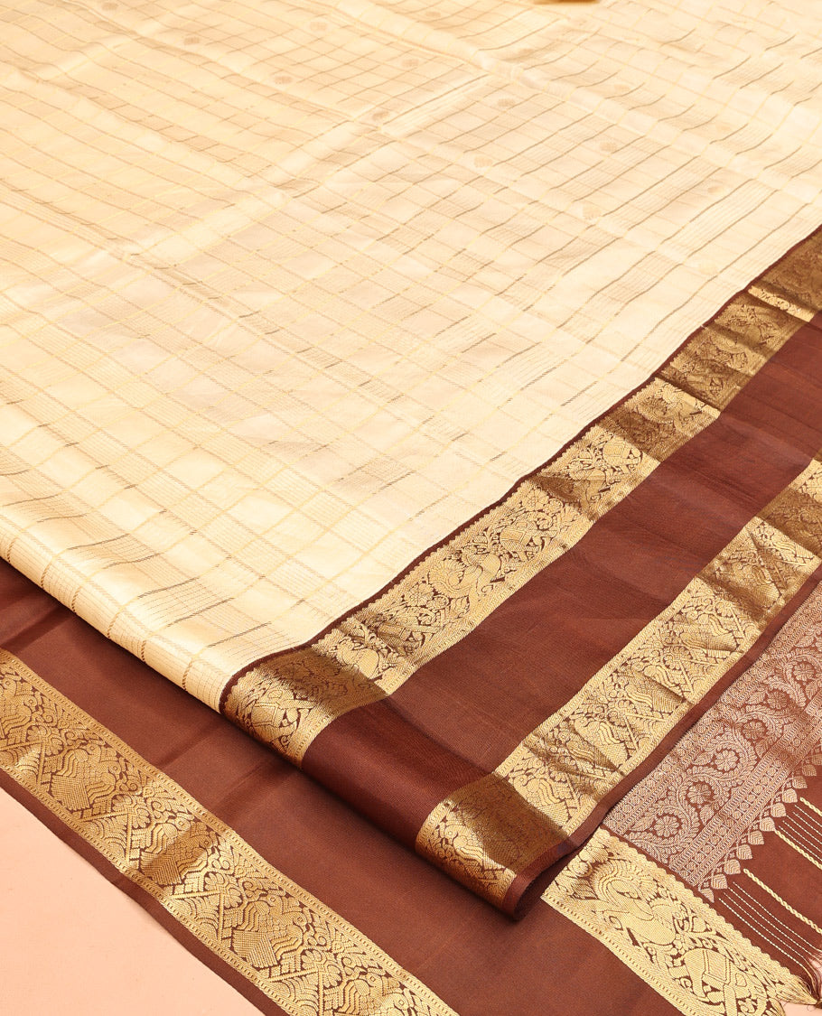 Cream Vasundhara Silk Saree, Enthralled with Zari Buttas Enclosed Checks All Over Its Body, Complemented by a Contrast Rettai Pettu Border of Muthu, Banaras, and Iruthalai Pakshi Designs, a Grand Pallu, and Paired with a Contrast Blouse