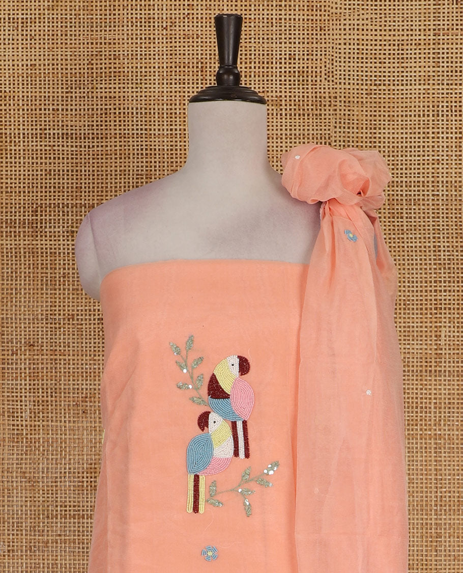 Peach net kota material chudidar set, macaw parrot, and flower motifs, multi-color sugar bead embroidered top, plain santoon bottom, and sugar bead embroidered dupatta