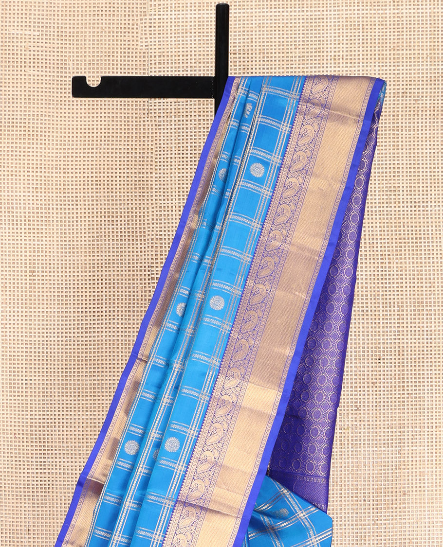 Blue Vasundhara Lite-Silk Mix Saree, Spotlighted with Yaanai, and Chakram Butta Enclosed Checks, Complemented by a Contrast Border of Thilakam, Poun, and Mayil Designs, Pallu Highlighted by Geometric Designs, and Paired with a Contrast Blouse
