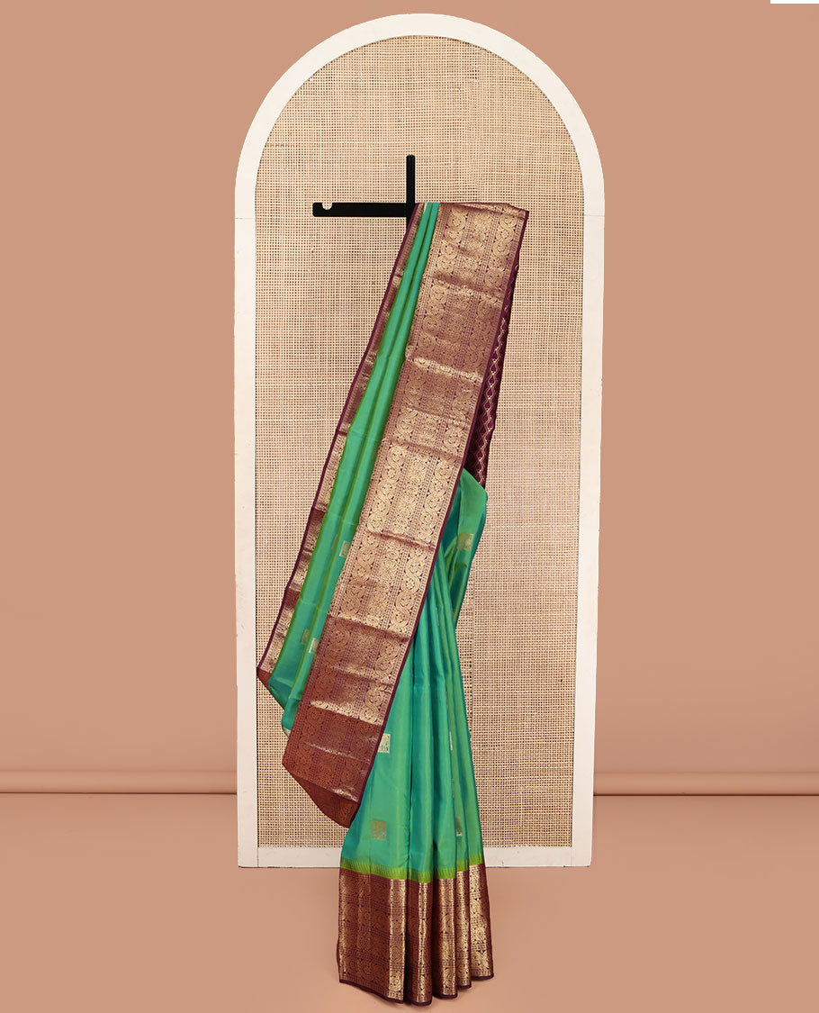 Sea Green Vasundhara Silk Saree, Accentuated with Zari Buttas All Over Its Body, Complemented by Contrast Border of Ara Bogudi, Banaras, Jada Nagam and Dhavana Kodi Designs, Pallu of Intricate Designs, and Paired with a Contrast Blouse