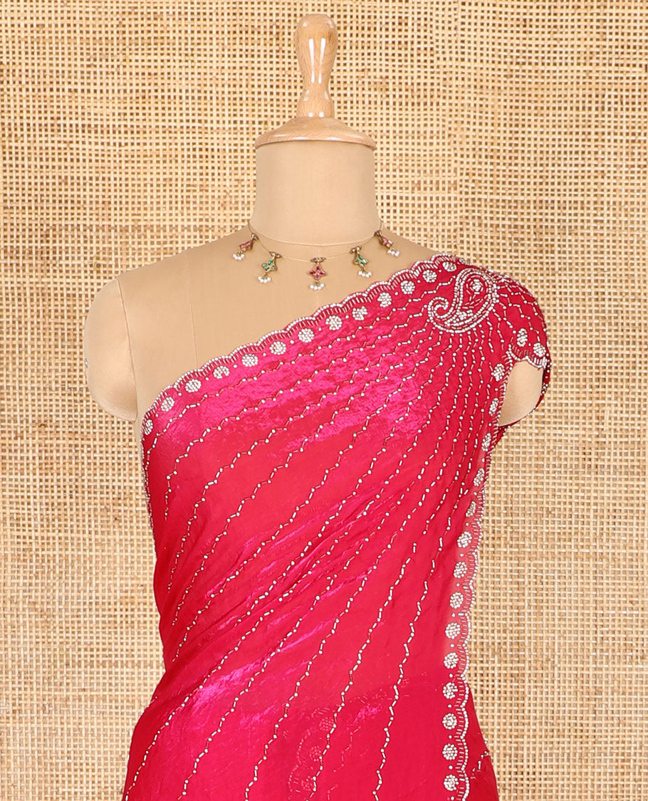Rani pink micro-stone work fendy chiffon saree with paisley stone work on its shoulder, a scallop stone work border, a butterfly style pallu, and a matching stone work blouse