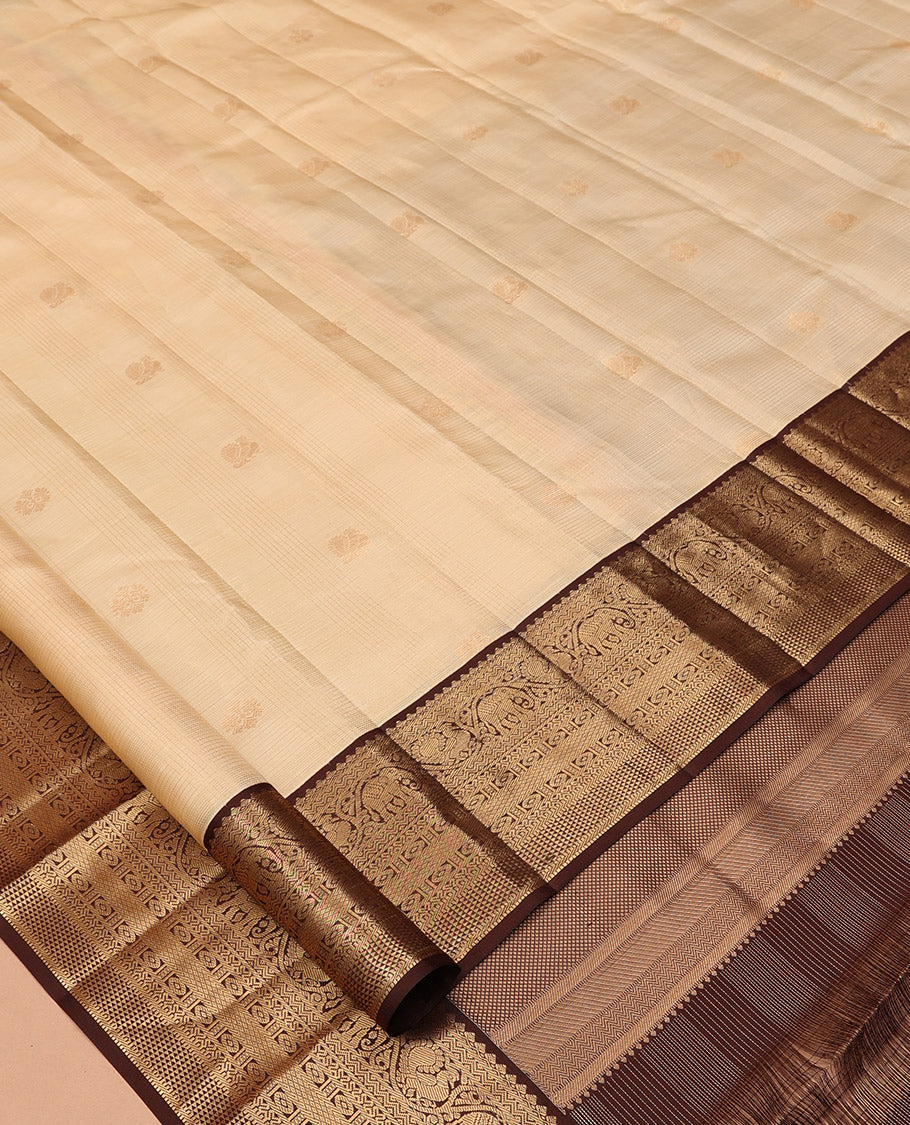 Sandal Vasundhara Silk Saree, Sparsely Sparkled with Zari Checks and Mayil Buttas, a Contrast Border of Thilakam Mokku, Banaras, Neli, Mayil, Yaanai, Mayil Kann, and Ara Maadam Designs, Grand Pallu, and a Contrast Blouse