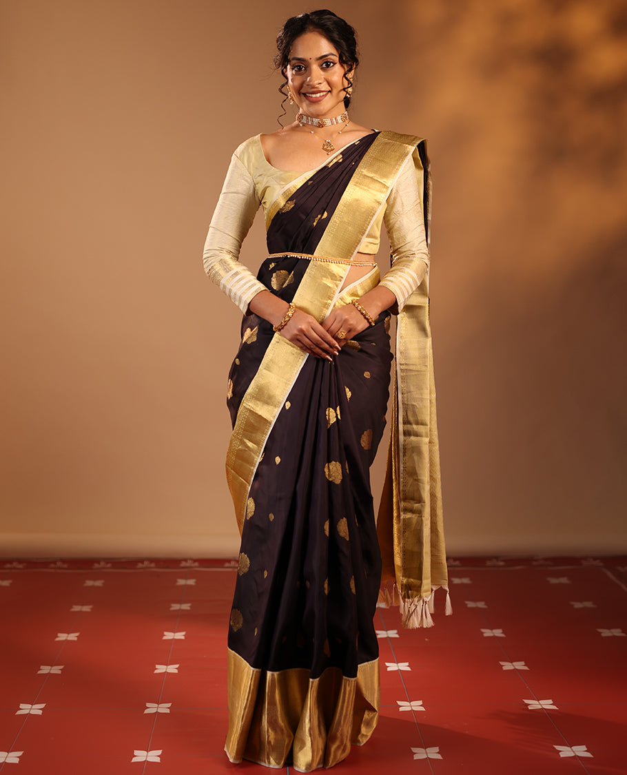 Dark Chocolate Brown Vasundhara Silk Saree Highlighted with Zari Buttas, Decked Up with a Contrast Border Featuring Rekku, Mayil Kann, Mayil, and Rudraksham Designs, Zari-Elevated Pallu, and Complemented with a Zari-Embellished Blouse