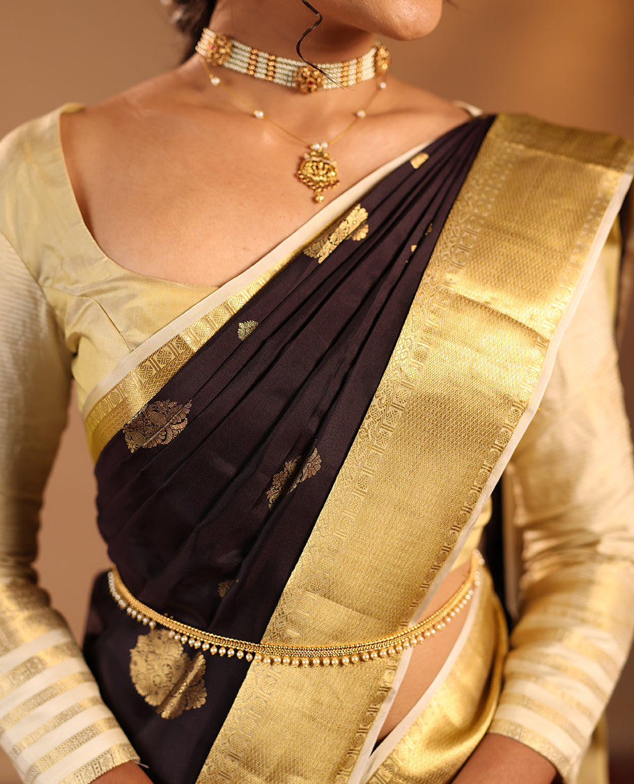 Dark Chocolate Brown Vasundhara Silk Saree Highlighted with Zari Buttas, Decked Up with a Contrast Border Featuring Rekku, Mayil Kann, Mayil, and Rudraksham Designs, Zari-Elevated Pallu, and Complemented with a Zari-Embellished Blouse