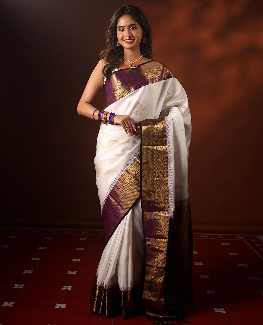 White Silk Saree Highlighted with All-Over Zari Buttas, Contrast Border Features Thazampoo Rekku, Yaanai, Mayil, and Muthu Designs, with a Zari-Enriched Jaal Pallu