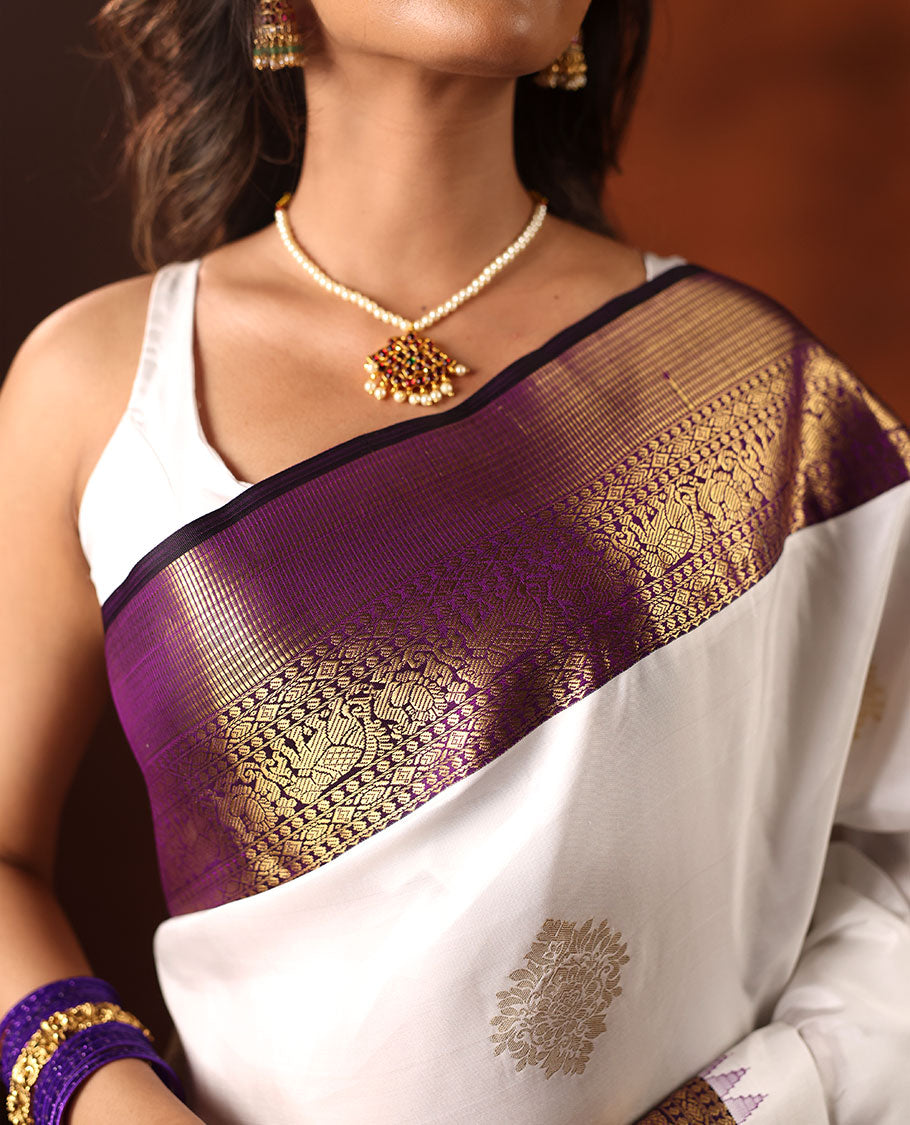 White Silk Saree Highlighted with All-Over Zari Buttas, Contrast Border Features Thazampoo Rekku, Yaanai, Mayil, and Muthu Designs, with a Zari-Enriched Jaal Pallu