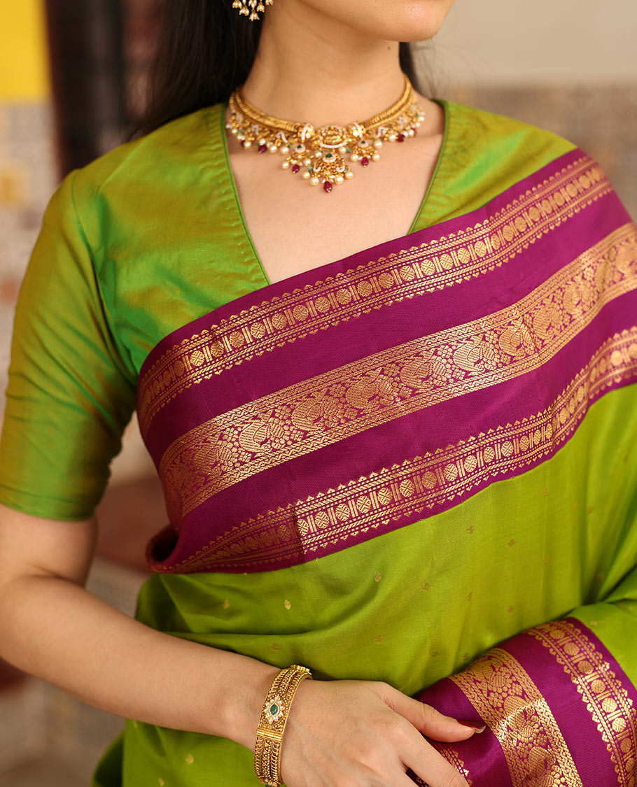 Parrot Green Vasundhara Silk Saree Richly Detailed with Zari Buttas, Complemented with Varisai Pettu Border Featuring Rekku, Muthu, Banaras, Rudraksham, and Mayil Designs, Majestically Zari Woven Pallu, and a Contrast Blouse