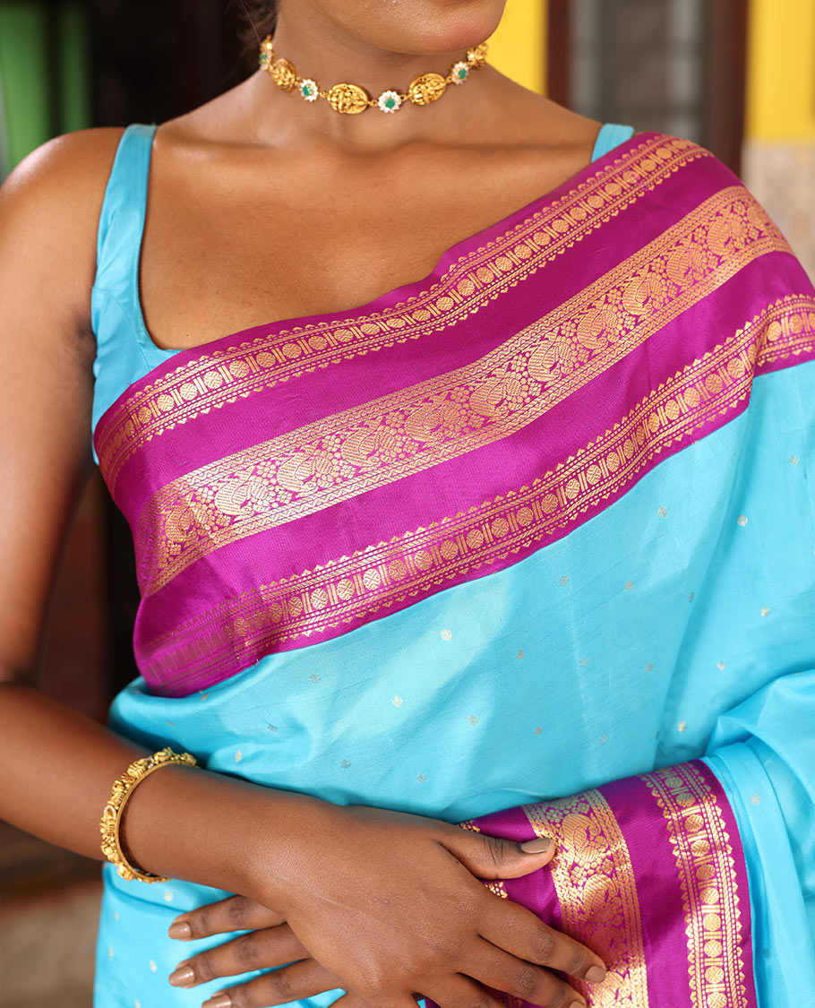 Blue Vasundhara Silk Saree Gracefully Embellished with Zari Buttas, Complemented by a Varisai Pettu Border Featuring Rekku, Muthu, Banaras, Rudraksham, and Mayil Designs, Majestically Woven with a Zari-Designed Pallu, and Paired with a Contrast Blouse