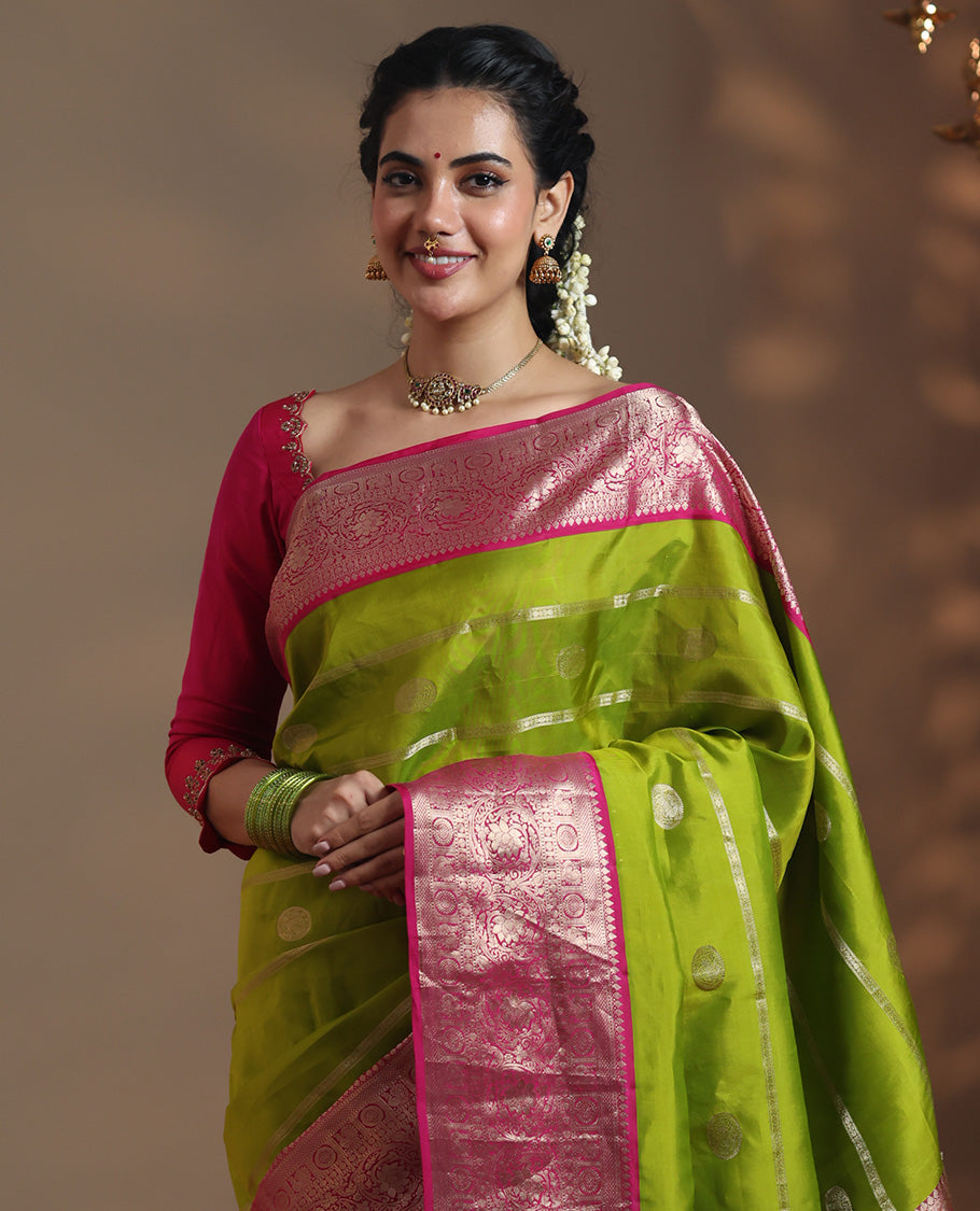 Parrot Green Vasundhara Silk Saree Featuring Veldhari and Round Kuthirai Motifs, Complemented by a Contrast Border of Thilakam Mokku, Muthu, Annam Chakram, and Kodi Visiry Designs, Pallu Elevated with Floral Designs, and Paired with a Contrast Blouse