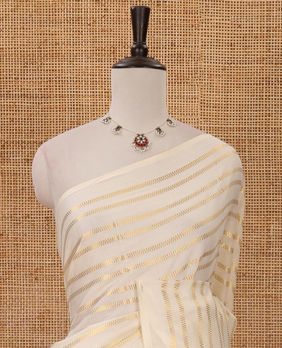 Borderless cream Veldhari-style striped Kerala cotton saree, zari design pallu with green tussels & zari design blouse