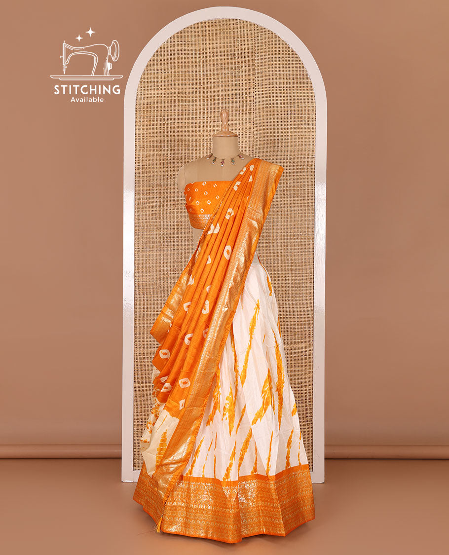 Cream and yellow semi-tussar half-saree, shibori printed with contrast geometric patterned bordered skirt, bandhani printed blouse, and bandhani printed dhavani