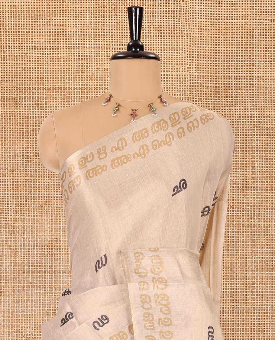 Cream-mustard Malayalam letter printed tissue saree, self-border and pallu steeped with Malayalam letter motifs, and a contrast plain blouse
