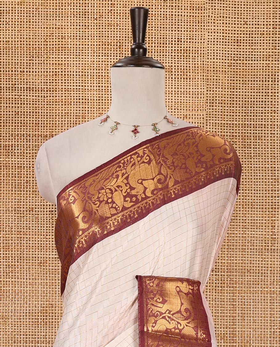 Half-white zari checked semi-taffeta silk saree, contrast maroon deer motifs woven border, striped pallu & contrast striped zari border blouse