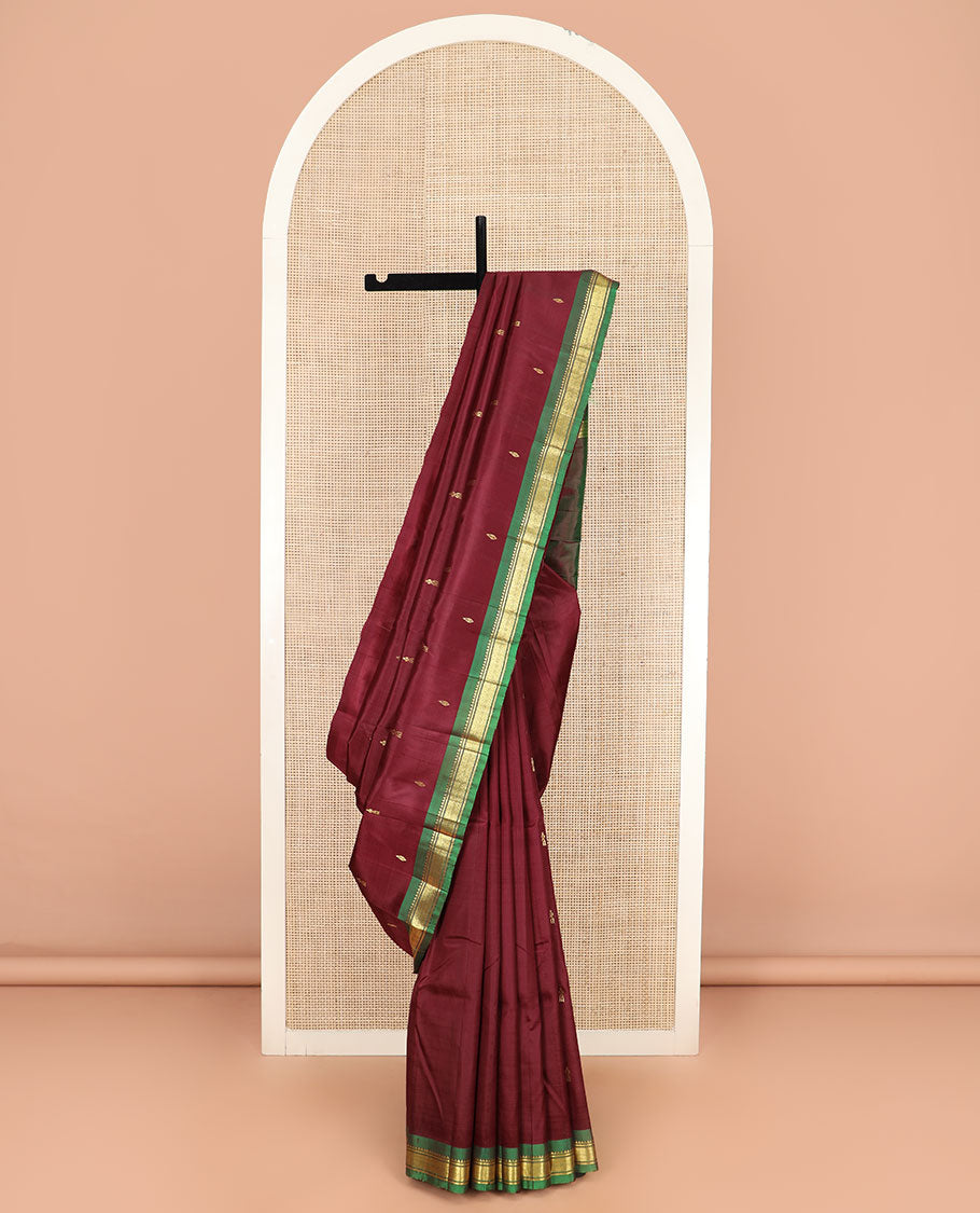 Maroon Kanchipuram Silk Saree Elevated with Zari Buttas All Over Its Body, Complemented by Contrast One-Sided Border of Rekku, Banaras, and Mayil Kann Designs, Pallu of Zari Designs, and Comes Without a Blouse