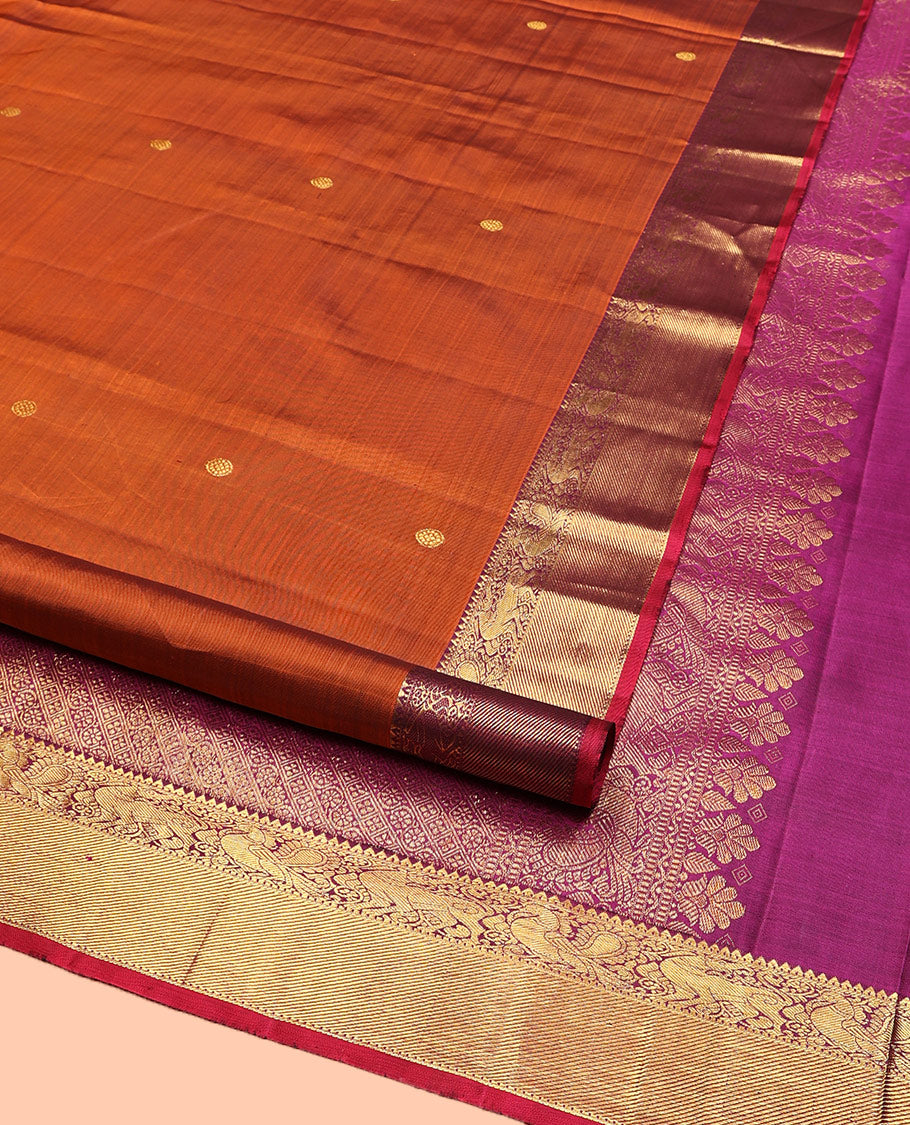 Orange Kanchipuram Silk Saree, Detailed with Chakram Buttas All Over Its Body, Complemented by Contrast Border of Rekku, Muthu, Mayil, and Yaali Designs, Pallu of Kodi Visiry and Lavangam Designs, and Paired with a Contrast Blouse