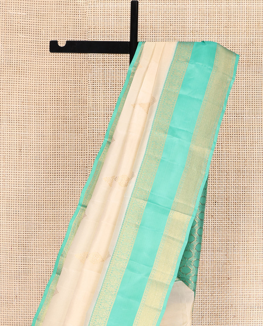 Cream Vasundhara Lite Silk Mix Saree, Gracefully Embellished with Zari Buttas All Over Its Body, Complemented by a Contrast Rettai Pettu Border of Thilakam Mokku, Kodi Visiry, and Kamalam Designs, Grand Jaal Design Pallu, and Paired with a Contrast Blouse