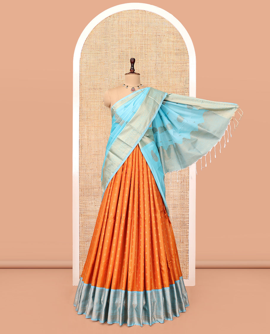 Orange Art Silk Half-Saree Pavadai Material Features a Zari-Buttas Skirt, a Contrast Traditional Border, Contrast Blouse, and Intricate Dhavani