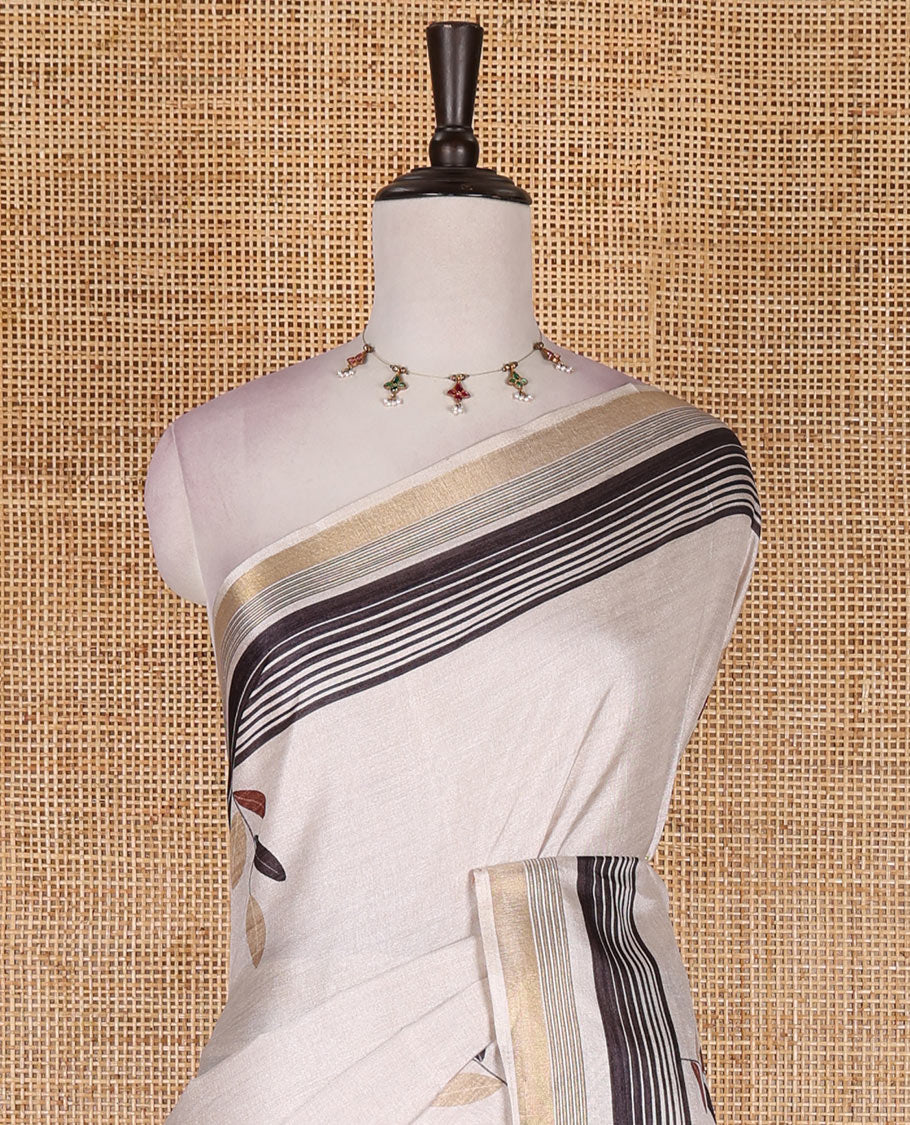 Cream leaf themed printed soft tussar saree, contrast golden zari horizontally striped border, dual color textured pallu, and contrast plain blouse