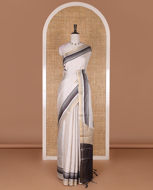 Cream leaf themed printed soft tussar saree, contrast golden zari horizontally striped border, dual color textured pallu, and contrast plain blouse