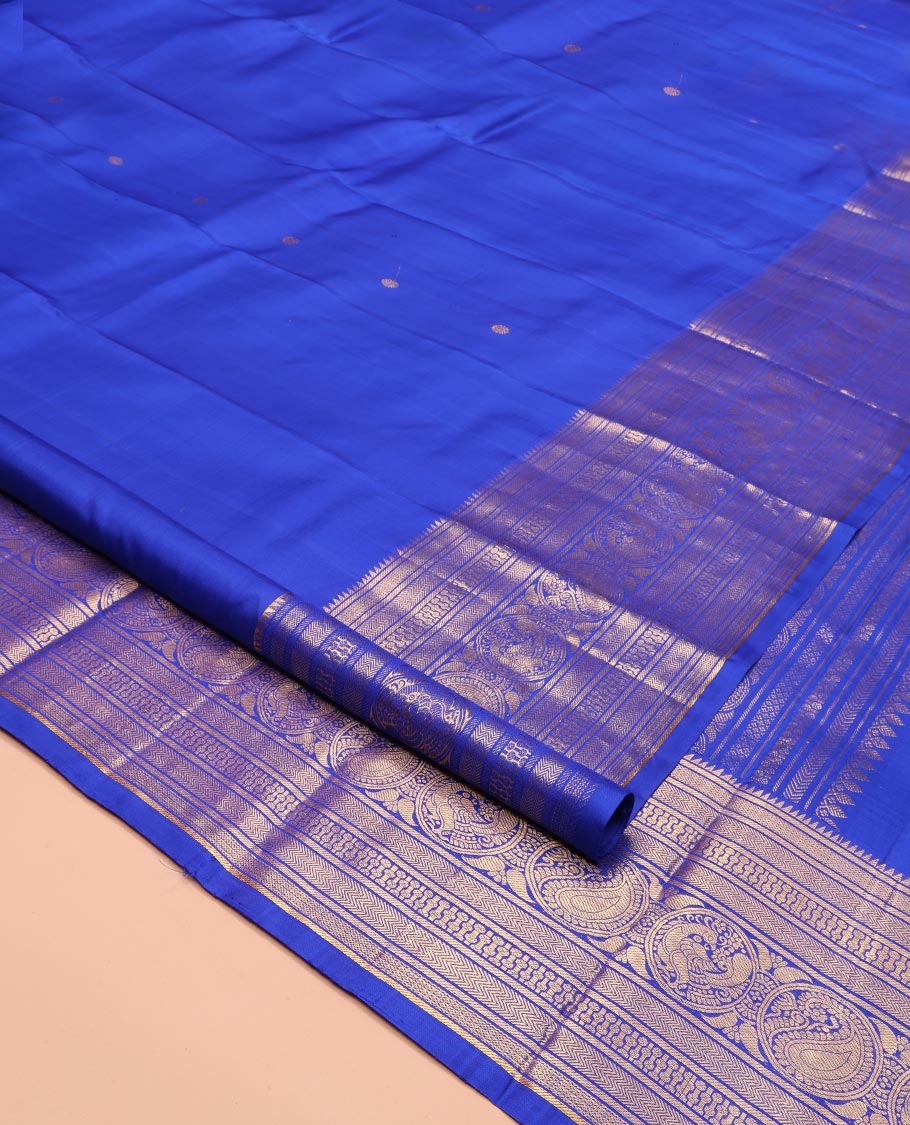 Blue Kanchipuram Silk Saree, Bedecked with Zari Buttas All Over Its Body, Highlighted by a Zari Border of Rekku, Vanki, Round Mayil, and Poun Manga Designs, Pallu of Zari Designs, and Paired with a Matching Blouse