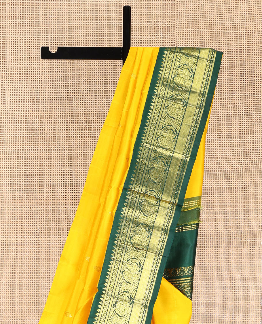 Yellow Kanchipuram Silk Saree, Decked Up with Zari Buttas, Complemented by Contrast One-Sided Korvai Border of Rekku, Banaras, Muthu, and Mayil Designs, Pallu Steeped with Round Mayil Designs, and Comes Without a Blouse