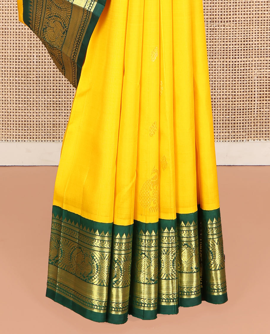 Yellow Kanchipuram Silk Saree, Decked Up with Zari Buttas, Complemented by Contrast One-Sided Korvai Border of Rekku, Banaras, Muthu, and Mayil Designs, Pallu Steeped with Round Mayil Designs, and Comes Without a Blouse