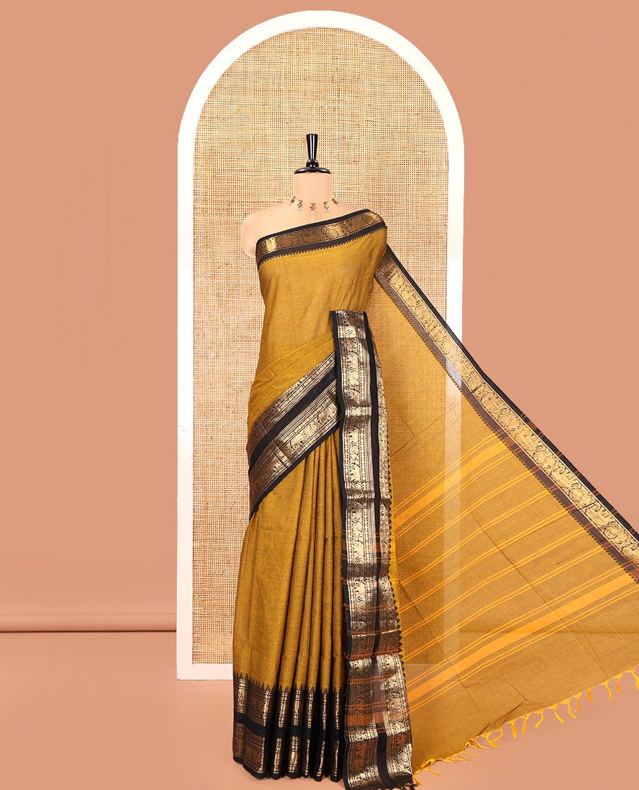 Mustard Plain Chettinad Cotton Saree, Complemented by a Contrast Rettai Pettu Temple Antique Gold Zari Border of Coin, Elephant, and Peacock Designs, Subtly Striped Pallu, and Paired with a Matching Blouse