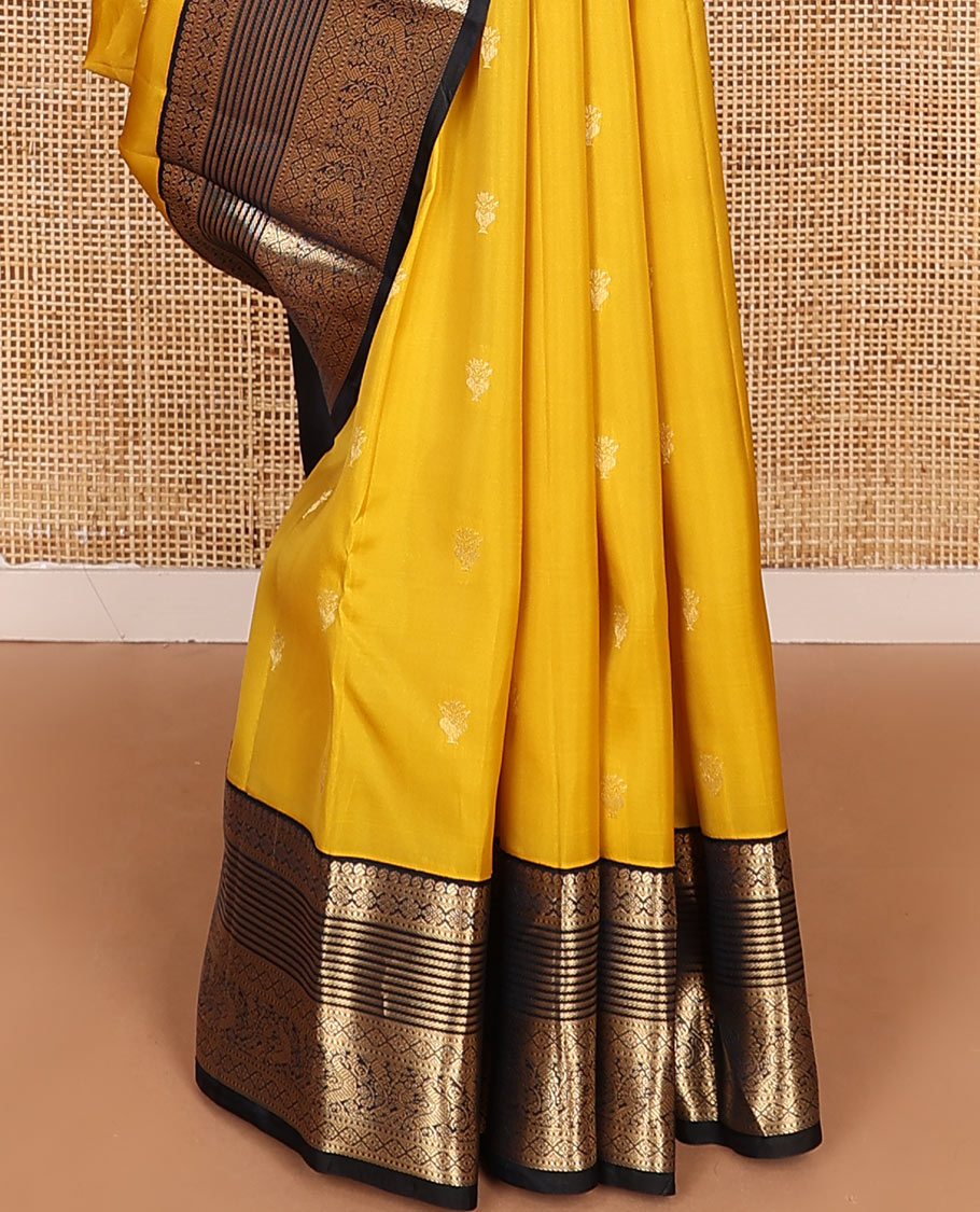 Yellow Vasundhara Lite-Silk Mix Saree Decked Up with Zari Buttas, Complemented by a Contrast Black Border Depicting Manga, Muthu, Kamalam, Banaras, Diamond, and Mayil Designs, Pallu Steeped with Diagonal Leaf Vines, and a Contrast Blouse