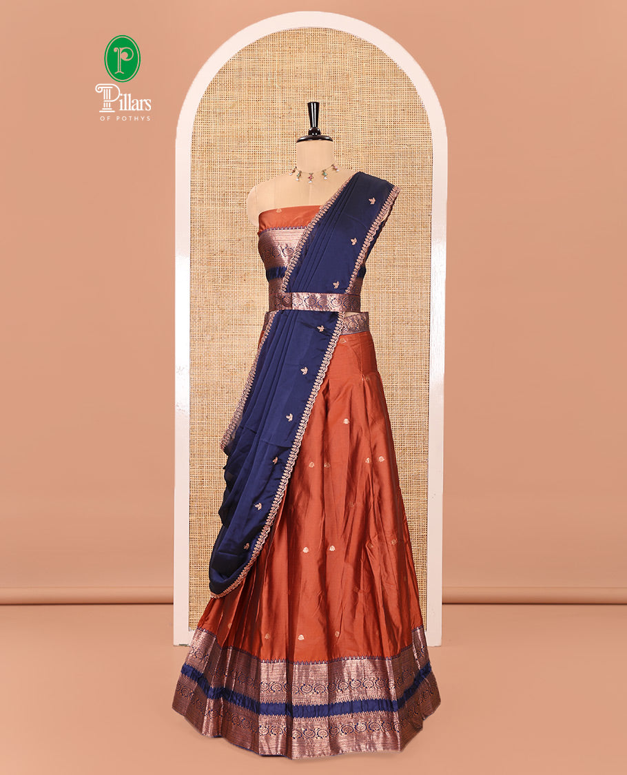 Rust and Blue Semi-Banarasi Half-Saree Featuring Zari Buttas Skirt, Complemented by Contrast Rettai Pettu, Traditional Border of Floral Creeper Designs, Paired with a Matching Blouse, and a Satin Georgette Embroidered Scallop Dhavani