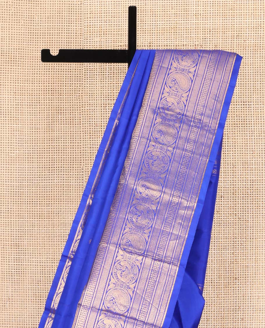 Blue Kanchipuram Silk Saree, Bedecked with Zari Buttas All Over Its Body, Highlighted by a Zari Border of Rekku, Vanki, Round Mayil, and Poun Manga Designs, Pallu of Zari Designs, and Paired with a Matching Blouse