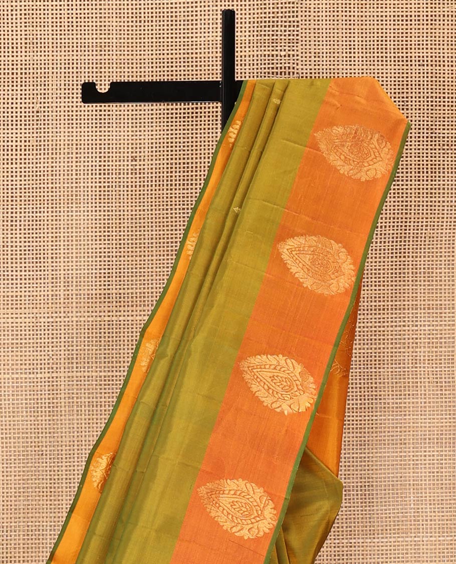 Green Kanchipuram Silk Saree, Sparsely Woven with Buttas All Over Its Body, Complemented by a Contrast Border of Thilakam Designs, Pallu Features Manga Zari Designs, and Paired with a Contrast Blouse