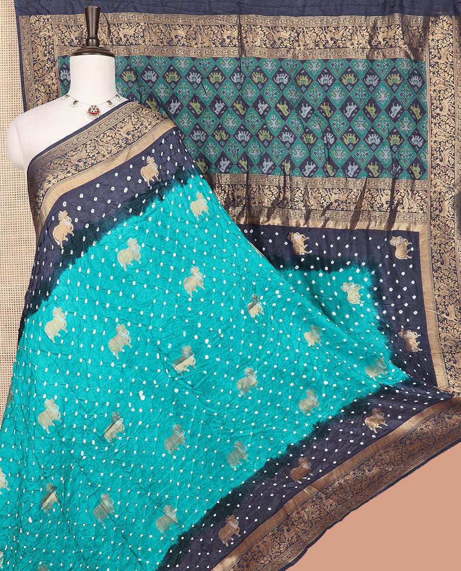 Blue bandhani dots and Pichwai cow motifs bandhani silk saree, contrast Pichwai cow and animal motifs zari border, and patola-style butta enclosed jaal pallu