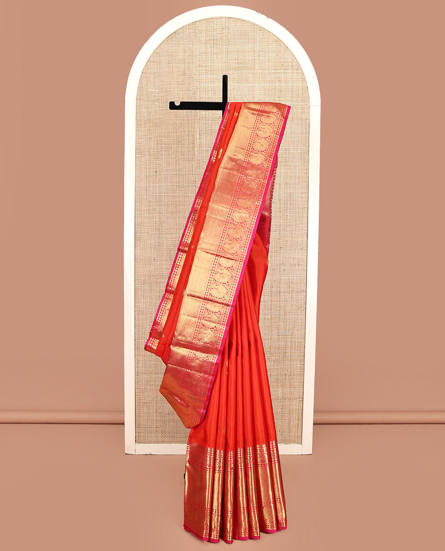 Orange Kanchipuram Silk Saree, Bedecked with Zari Buttas All Over Its Body, Complemented by a Contrast Border of Manga Mokku, Poun, Yaanai, and Mayil Designs, Grand Pallu of Kodi Visiry Designs, and Paired with a Contrast Blouse