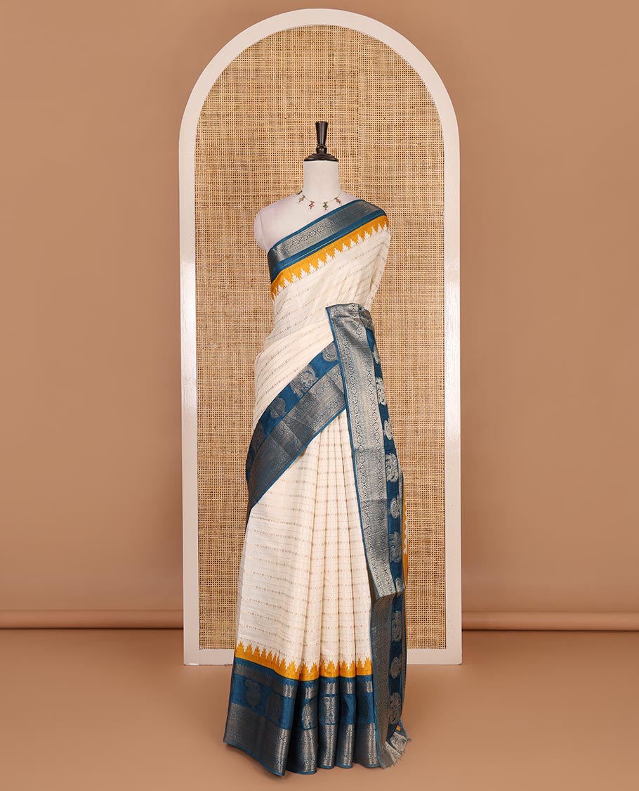 Half-white zari designs dola silk saree, contrast blue temple traditional border of peacock and elephant motifs, and temple pallu