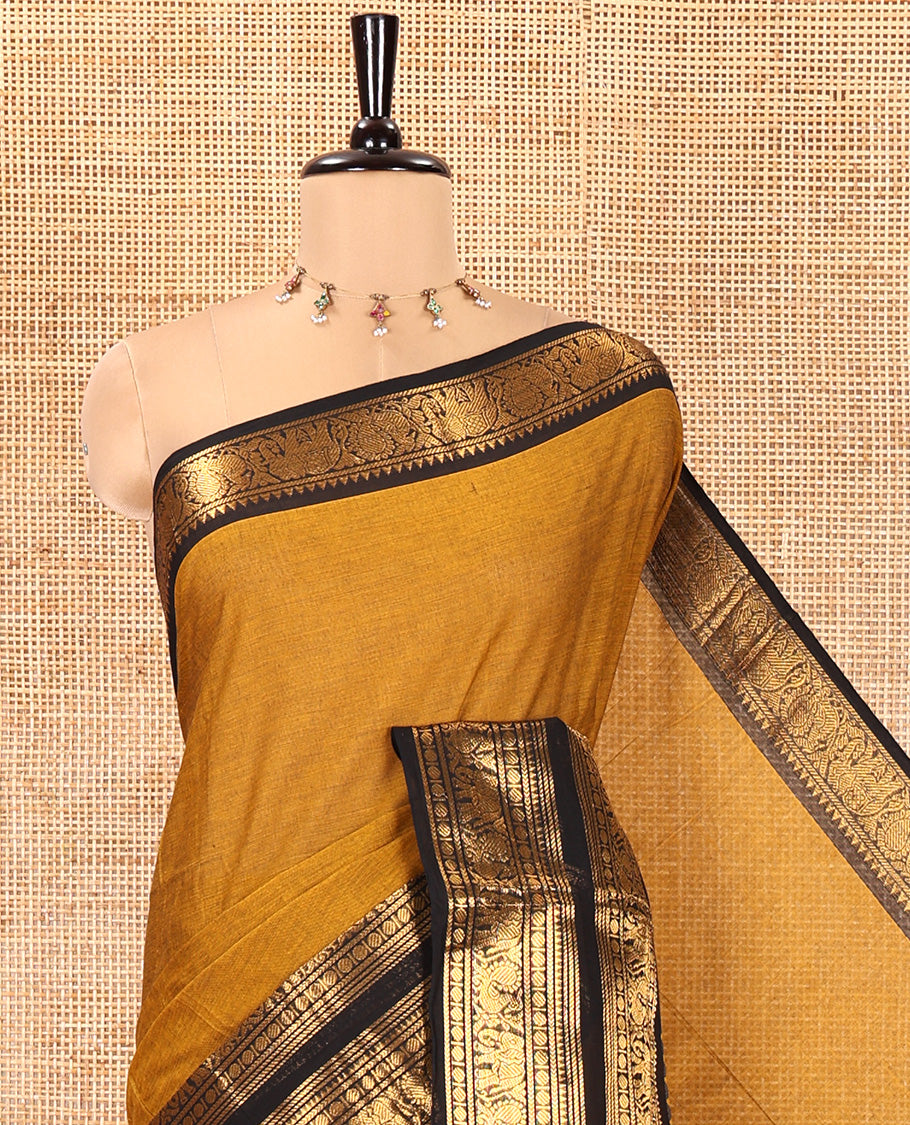 Mustard Plain Chettinad Cotton Saree, Complemented by a Contrast Rettai Pettu Temple Bright Gold Zari Border of Coin, Elephant, and Peacock Designs, Subtly Striped Pallu, and Paired with a Matching Blouse